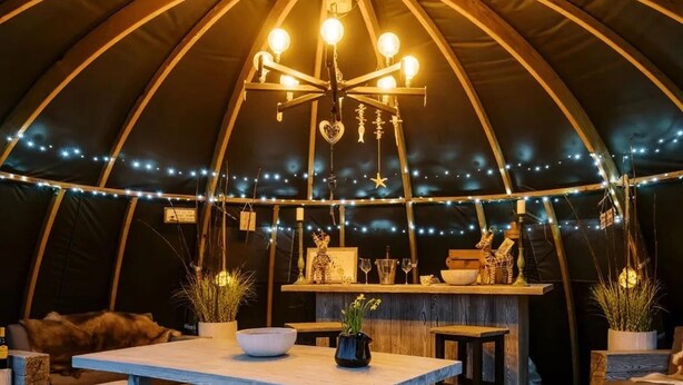 A cozy interior of a tent with a central bar, string lights, and rustic furnishings. - Shepherd's Hut- Hot Tub- Wellness Spa- Wood Burner (Nottingham)