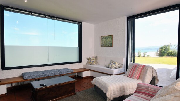 A modern living room with a large window, a sofa, a bench, and a coffee table. - A private,family-friendly estate with pool, garden,and all comforts—near the sea (Faros Avlidas)
