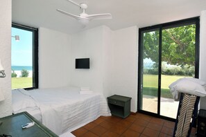 Ein Schlafzimmer mit Bett, Fernseher, kleinem Tisch, Nachttisch in Grün und Blick ins Freie.