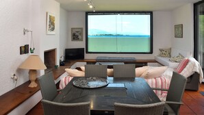 A dining area with a table and chairs, a television, and a large window with a view of the sea. - A private,family-friendly estate with pool, garden,and all comforts—near the sea (Faros Avlidas)