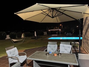 An outdoor patio with a pool, lounge chairs, and a table with candles.