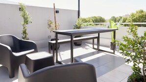 Un patio al aire libre con una mesa de metal, dos sillas y plantas en macetas.