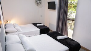 Une chambre d’hôtel avec deux lits, une télévision, un ventilateur et une fenêtre donnant sur l’extérieur.