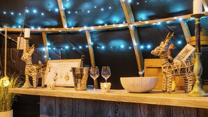 Un interior rústico con barra de madera, luces colgantes y un letrero de bienvenida.