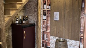A wine cellar with wooden shelves and a wine rack, a wooden barrel, and a refrigerator. - Charming house in the heart of Burgundy, close to Beaune and the wine route. (Demigny)