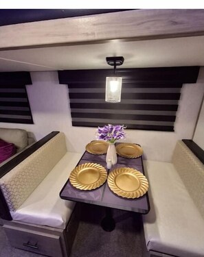 Enjoy a cozy dining experience with a central table, cushioned benches, and a stylish vase.