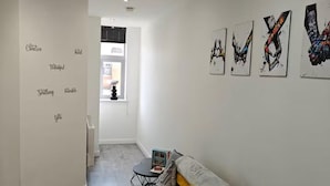 A modern living room with a grey sofa, a small table, and a rug. There are four artworks on the wall and a window with blinds. - Modern 1Br Sleeps3 - City Centre Location (Leicester)