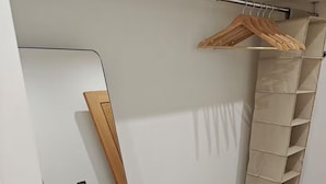 A closet with a wooden hanger rack and a beige storage unit. - Modern 1Br Sleeps3 - City Centre Location (Leicester)
