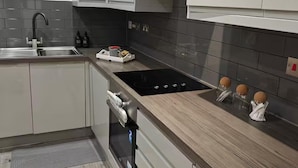 A modern kitchen with white cabinets, a black stove, and a wooden countertop. - Modern 1Br Sleeps3 - City Centre Location (Leicester)