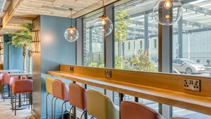 A modern bar area with wooden counters, colorful bar stools, and pendant lighting. - Premier Inn London Paddington - Paddington Station (London)