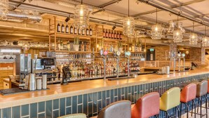 A bar with a long counter, multiple taps, and a variety of bottles and glasses. - Premier Inn London Paddington - Paddington Station (London)