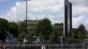 Un hôtel moderne, doté d’une enseigne bien visible, de grandes fenêtres et dont la façade reflète le ciel.
