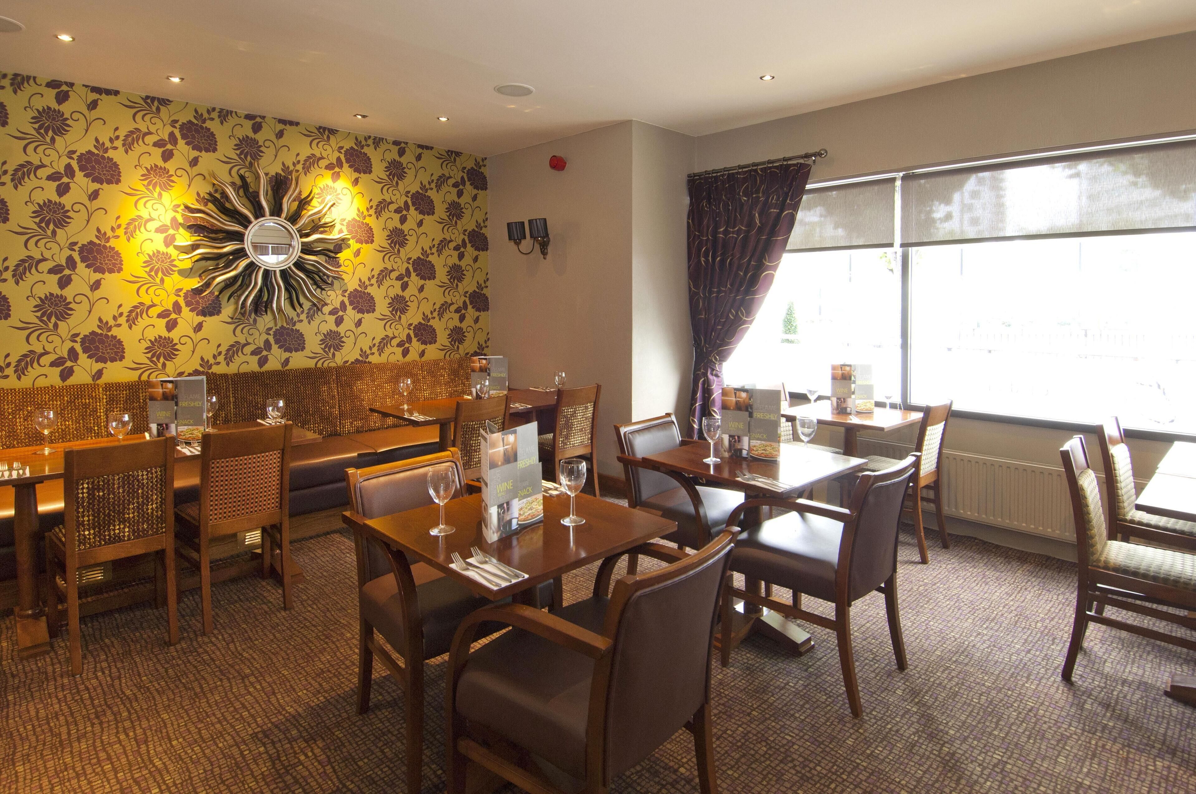 A dining area with tables and chairs, a sofa, and a decorative wall.
