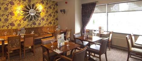 A dining area with tables and chairs, a sofa, and a decorative wall.