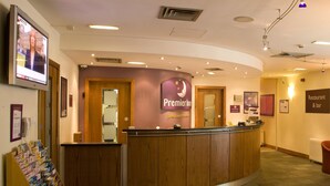 Un comptoir d’accueil d’hôtel avec une enseigne « Premier Inn », un téléphone, un présentoir à magazines et une enseigne « Restaurant et bar ».