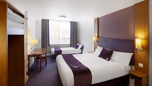 Une chambre d’hôtel avec deux lits, un bureau, une chaise et une fenêtre avec des rideaux.
