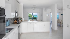 Een moderne keuken met witte kasten, een centraal eiland en uitzicht op zee.