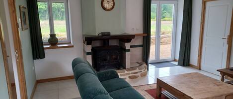 Una sala de estar con un sofá, una chimenea, un reloj y vistas al exterior.