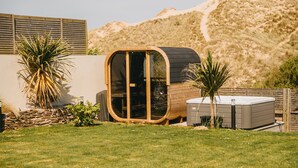 Een modern, gebogen houten constructie met glazen deuren, omgeven door een verzorgd gazon en woestijnplanten.