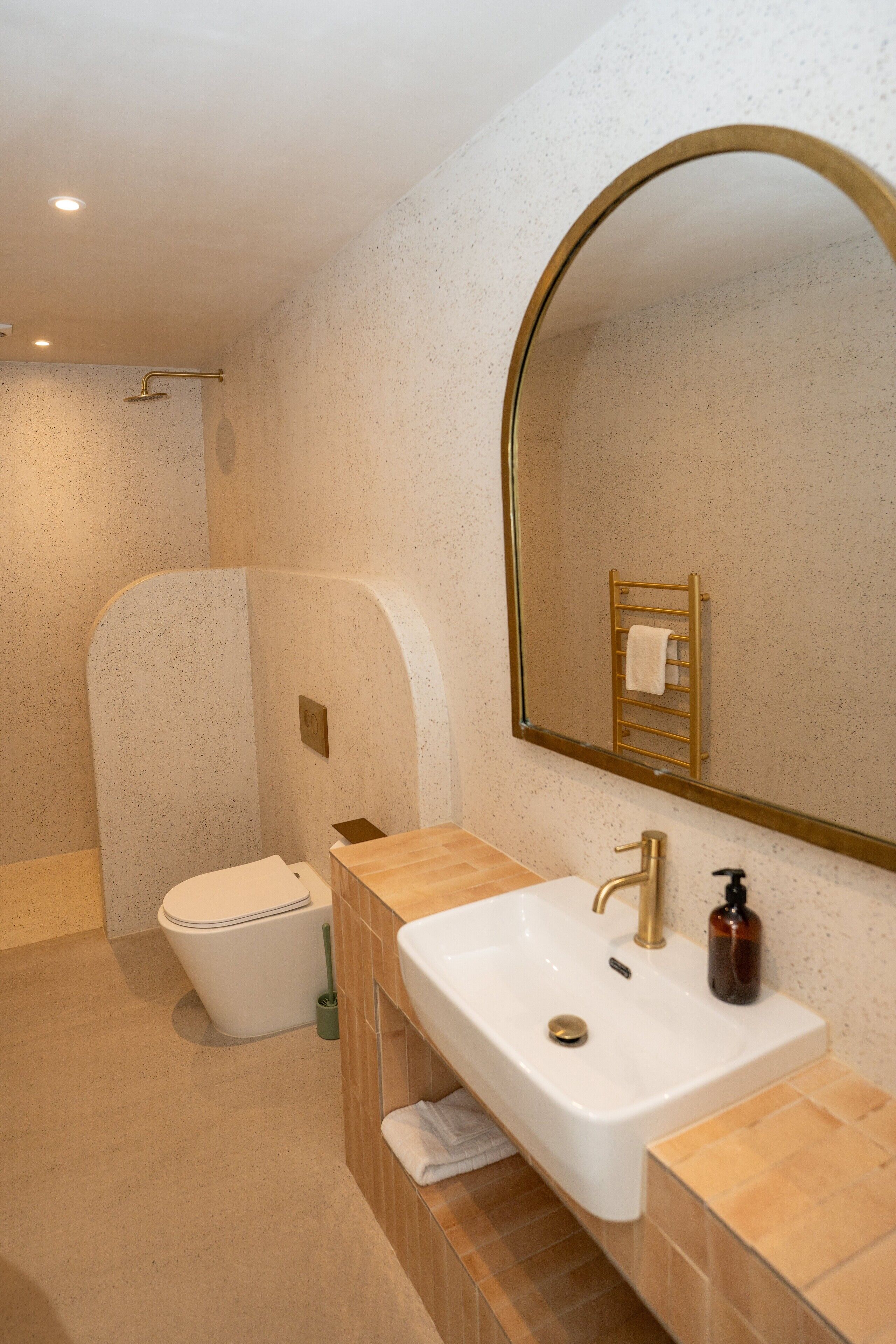 Une salle de bain moderne avec un lavabo blanc, des robinets dorés et un grand miroir.