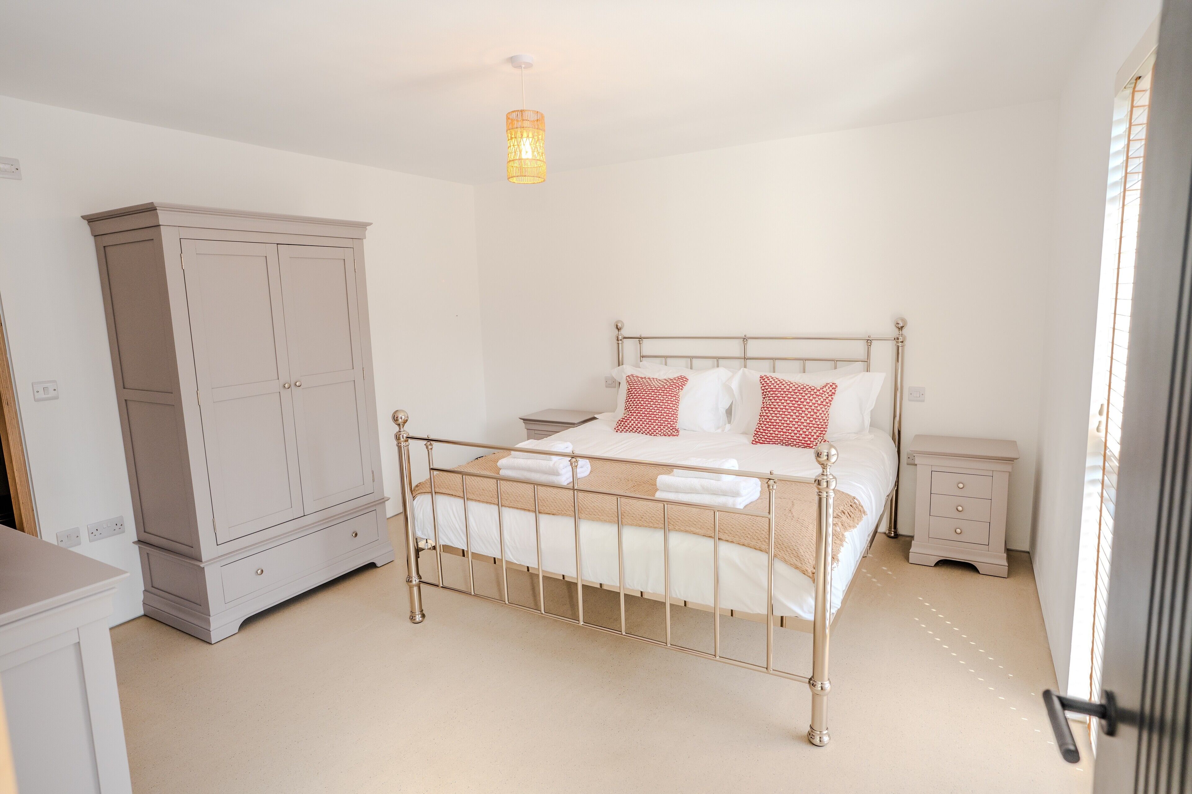 A bedroom with a bed, bedside tables, a wardrobe, and a hanging light fixture.