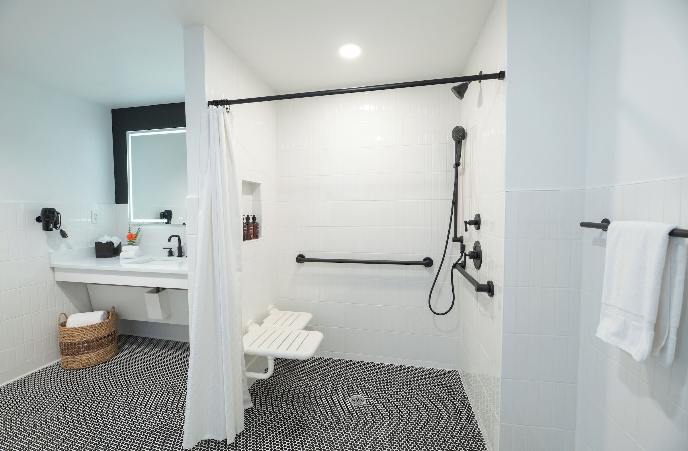 A modern bathroom with a white sink, mirror, and shower area.