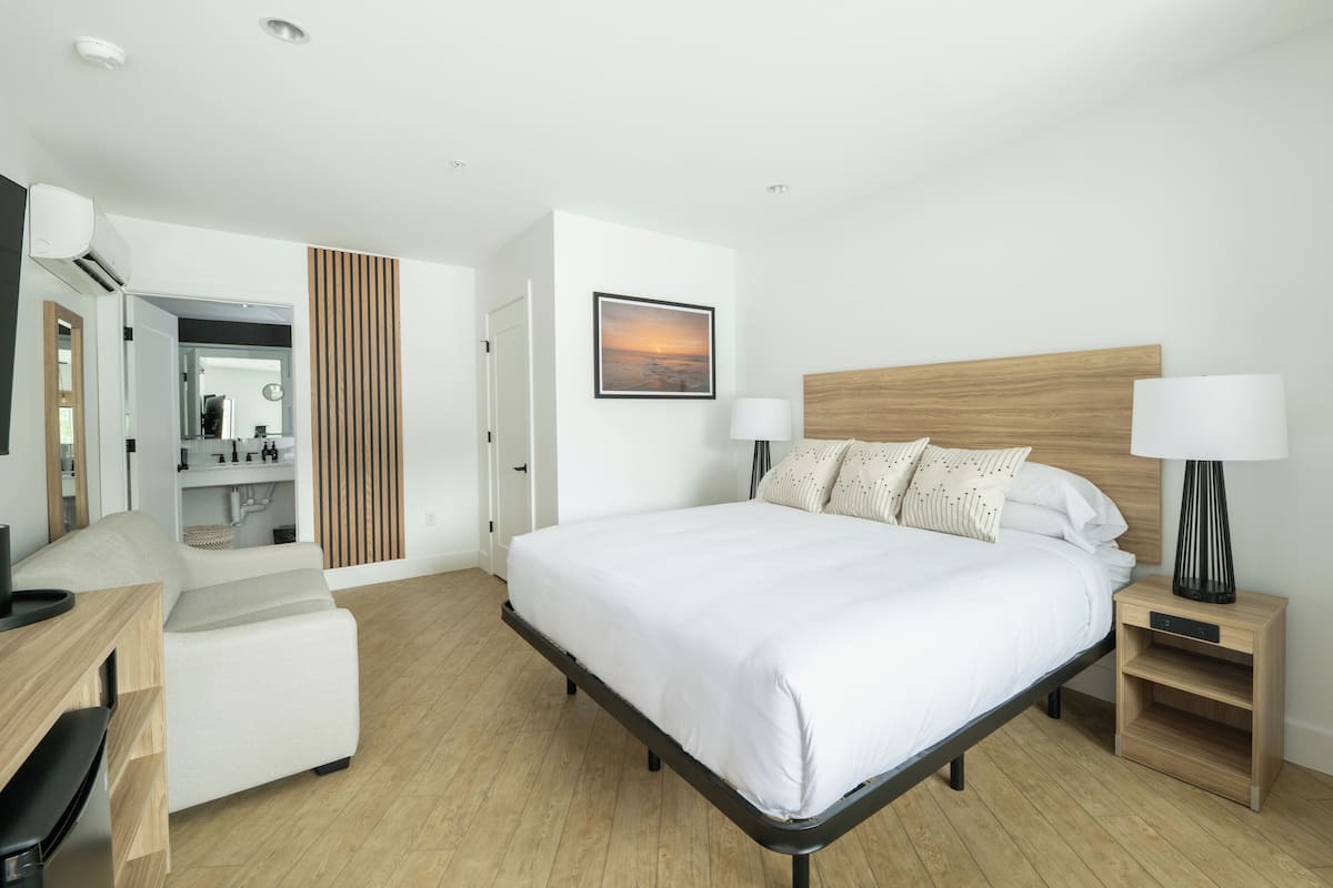 A modern hotel room with a large bed, bedside tables, a desk, and a mirror.