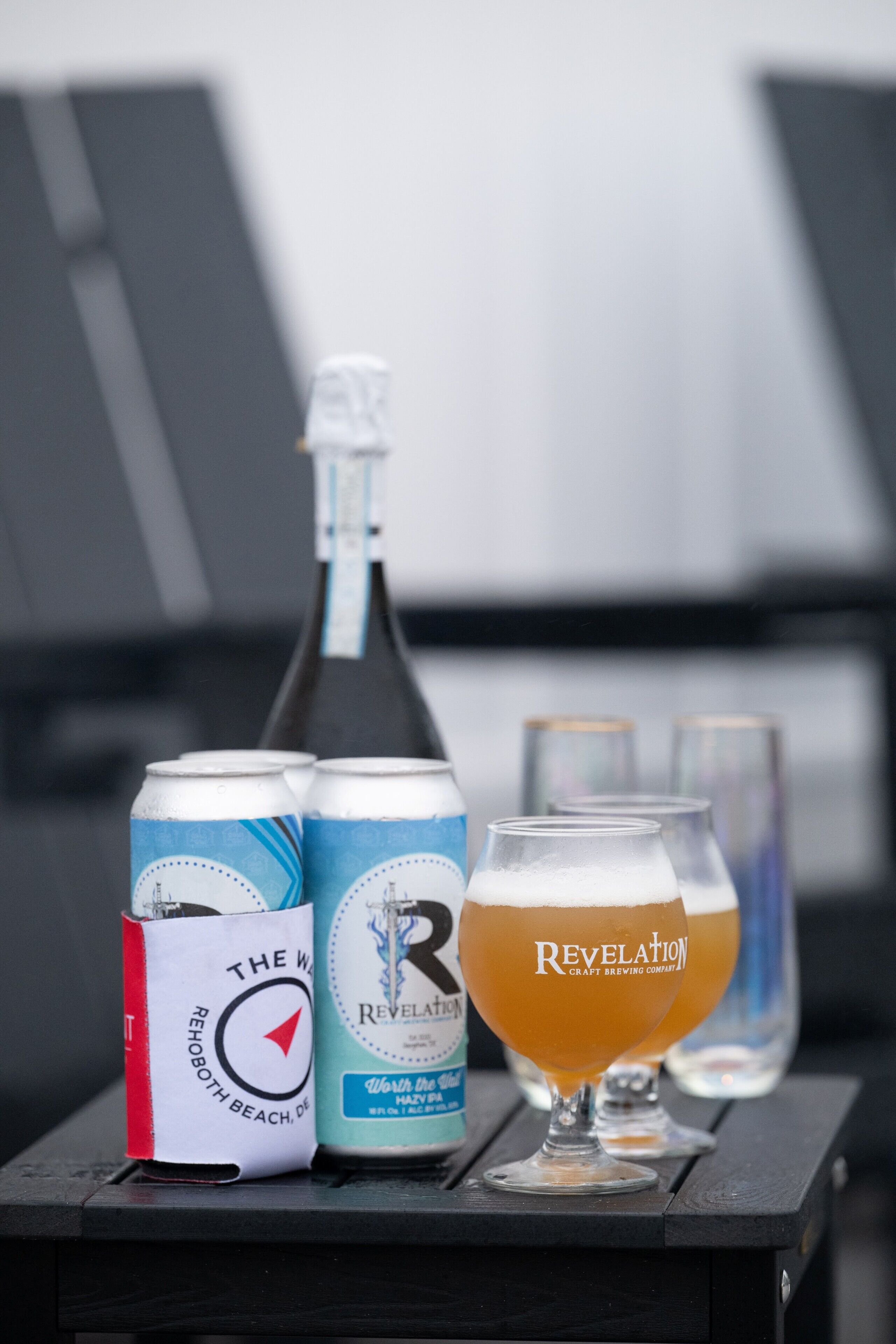 Une bouteille, deux canettes et deux verres sur une table.