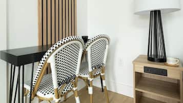 A modern room with a black table, two patterned chairs, a wooden sideboard, and a floor lamp.