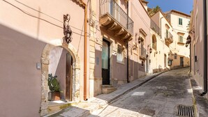 Uma rua de paralelepípedos estreita, ladeada por edifícios com portas em arco e varandas.