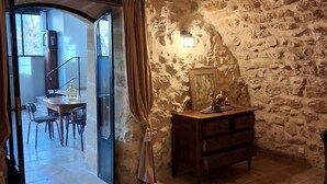 Un dormitorio con pared de piedra, una cama, un aparador y un escritorio con una silla.