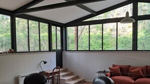 Un amplio salón con un gran ventanal, un sofá rojo, un sillón de cuero negro y una mesa de centro.
