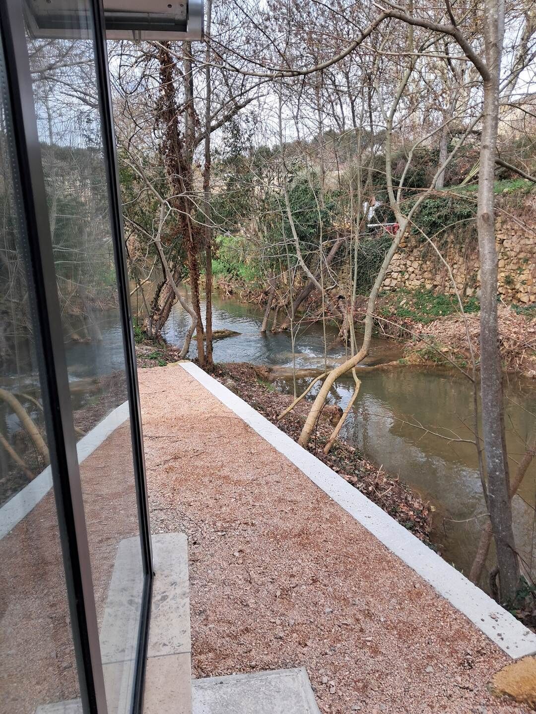 Blick auf einen Fluss mit einer Steinmauer und Bäumen.