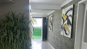 A hallway with a potted plant, tiled floor, and abstract art on the walls. - HNH HOTEL LUXURY EXPERIENCE VIP (San Andrés)