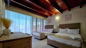 A hotel room with two beds, a wooden desk, and a large window with curtains. - HNH HOTEL LUXURY EXPERIENCE VIP (San Andrés)