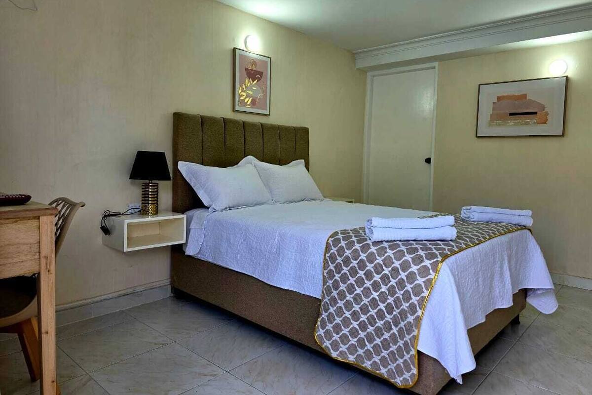 Une chambre d’hôtel avec un lit, une table de chevet, une lampe et des œuvres d’art murales.