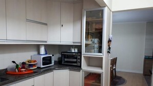 A compact kitchen with white cabinets, a microwave, a toaster oven, and a small refrigerator. - Ap Beira Mar - Ed Belo Mar - BC (Balneario Camboriu)