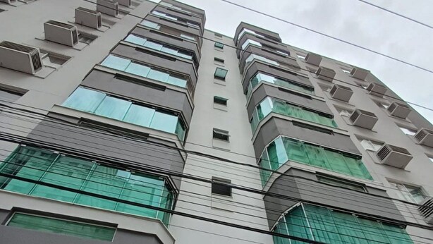 A multi-story building with a modern architectural design, featuring balconies and air conditioning units. - Ap Beira Mar - Ed Belo Mar - BC (Balneario Camboriu)