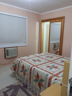 A bedroom with a bed, a window, a mirror, and a radiator. - Ap Beira Mar - Ed Belo Mar - BC (Balneario Camboriu)