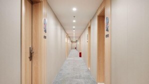 A long, narrow hallway with wooden doors on both sides, a grey carpet, and a red object on the floor. - yun jing Hotel (Shanghai Songjiang University Town) (Shanghai)