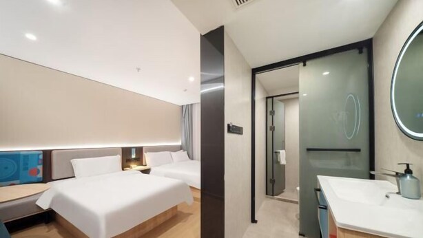 A modern hotel room with a large bed, a desk, a bathroom with a mirror and sink, and a glass door leading to another room. - yun jing Hotel (Shanghai Songjiang University Town) (Shanghai)