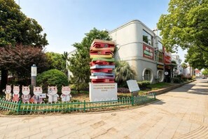 A building with a stack of colorful books, a green fence, and cartoon pig figures. - yun jing Hotel (Shanghai Songjiang University Town) (Shanghai)