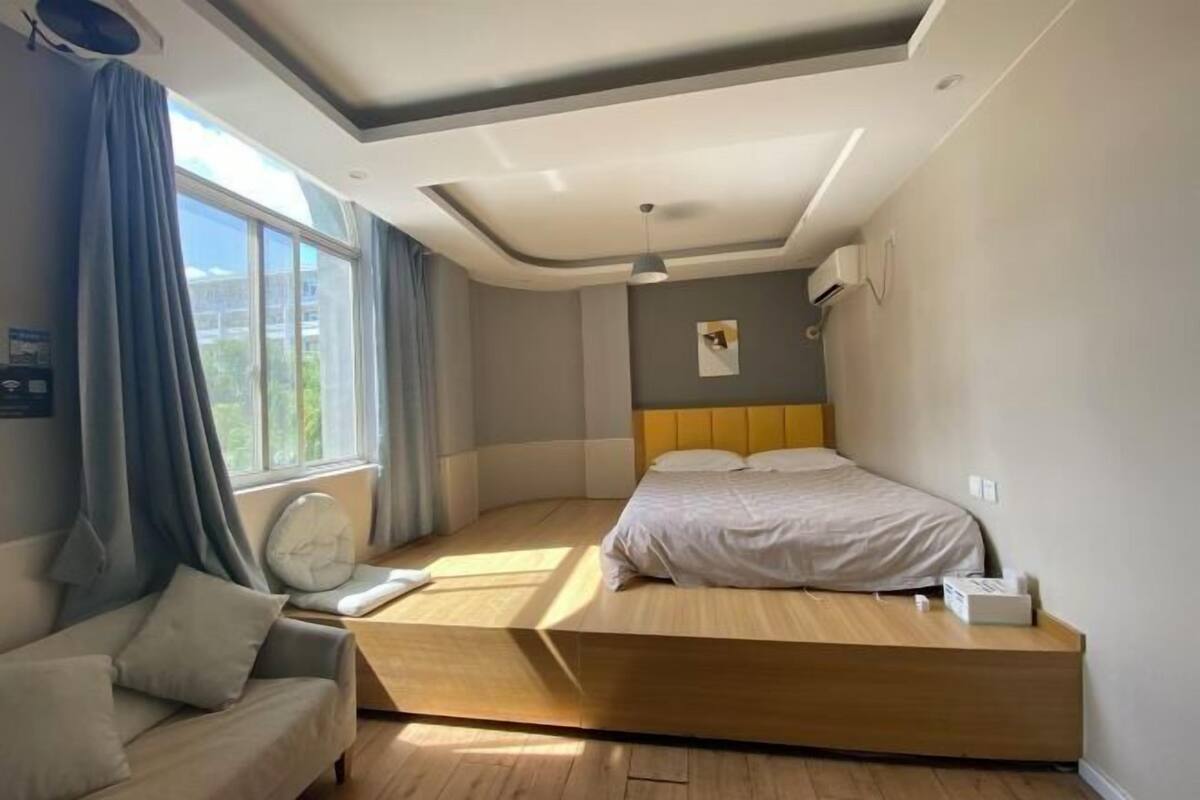 Ein modernes Schlafzimmer mit Bett, Sofa und Fenster.