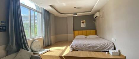 A modern bedroom with a bed, a sofa, and a window.