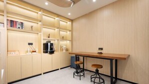 A modern kitchen with a wooden countertop, two stools, and built-in shelves with books and decorative items. - yun jing Hotel (Shanghai Songjiang University Town) (Shanghai)
