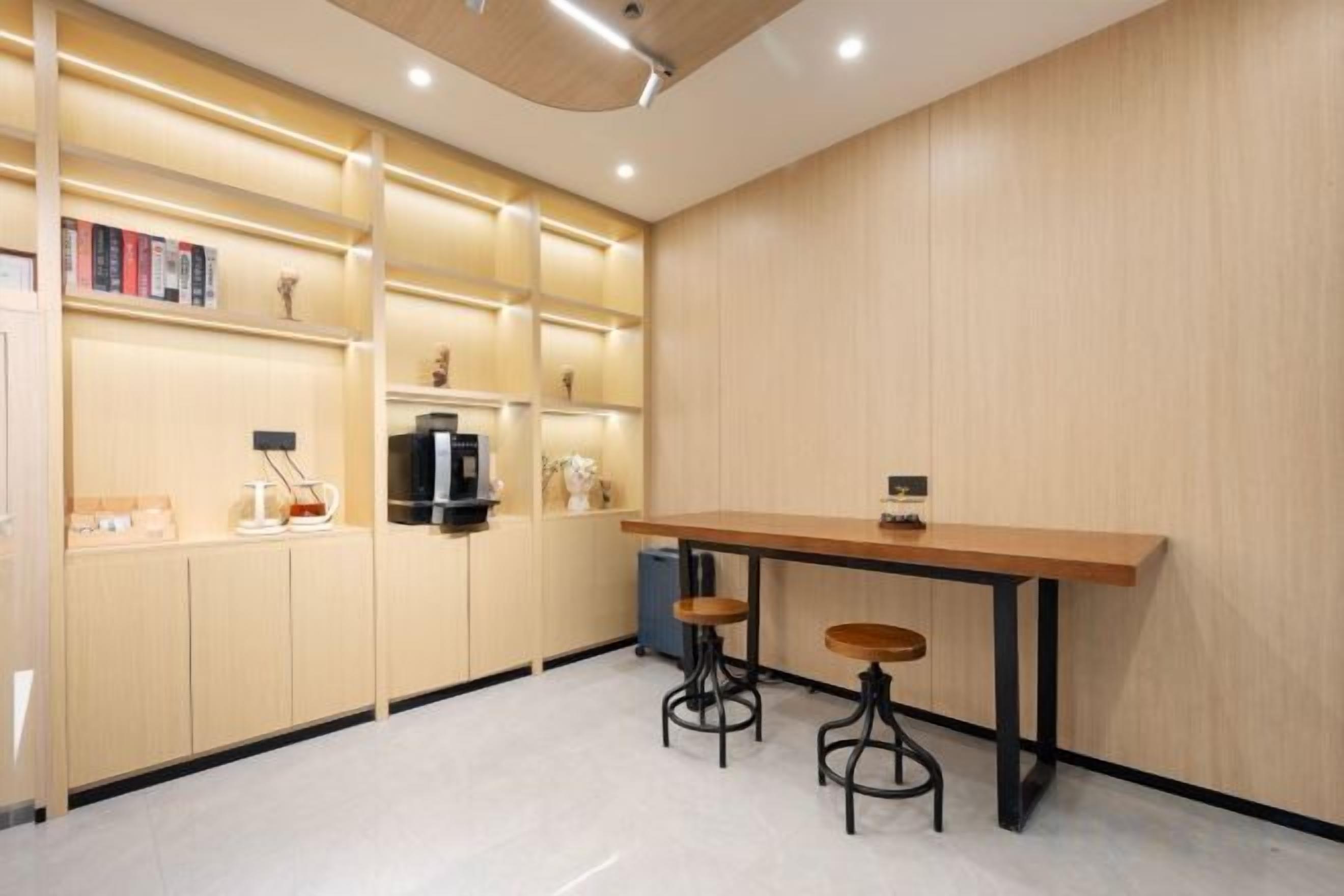 A modern kitchen with a wooden countertop, two stools, and built-in shelves with books and kitchen appliances.