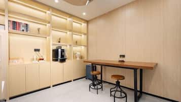 A modern kitchen with a wooden countertop, two stools, and built-in shelves with books and kitchen appliances.
