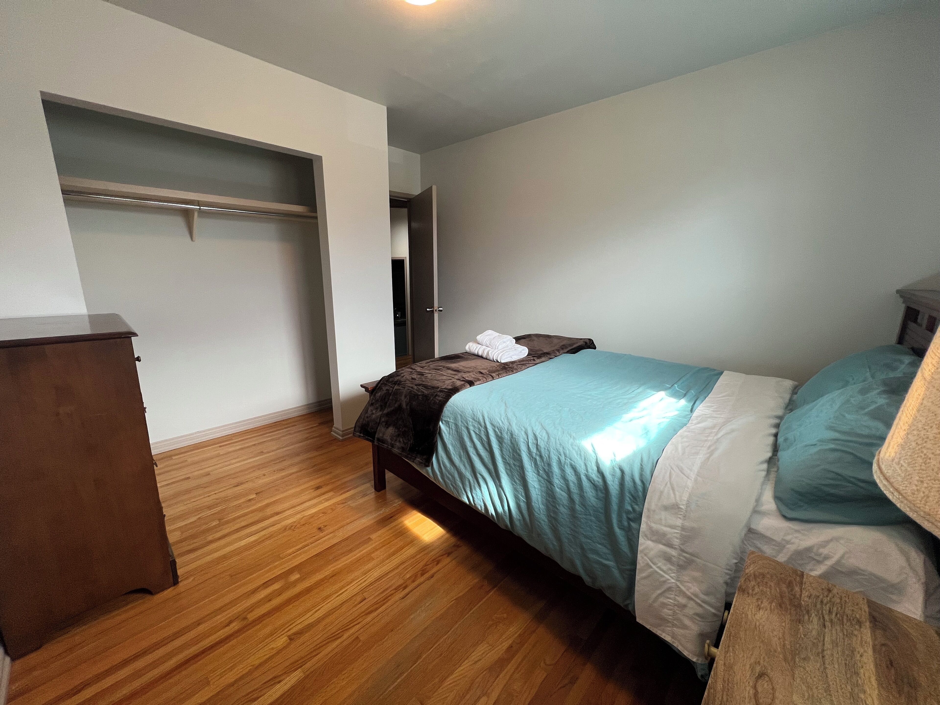 Une chambre à coucher avec un lit, une commode en bois et un dressing.