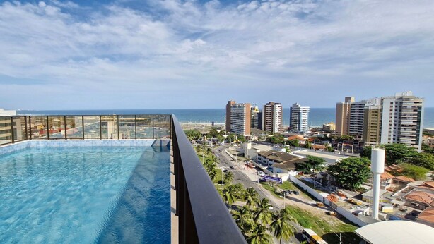 A rooftop pool with a city view, surrounded by high-rise buildings and palm trees. - COARM0102 - Smart Convenções (Salvador)