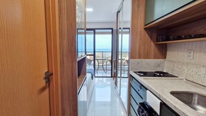 A modern kitchen with a view to the sea, a wooden door, and a granite countertop. - COARM0102 - Smart Convenções (Salvador)